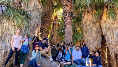 a group of students pose in front of palm trees